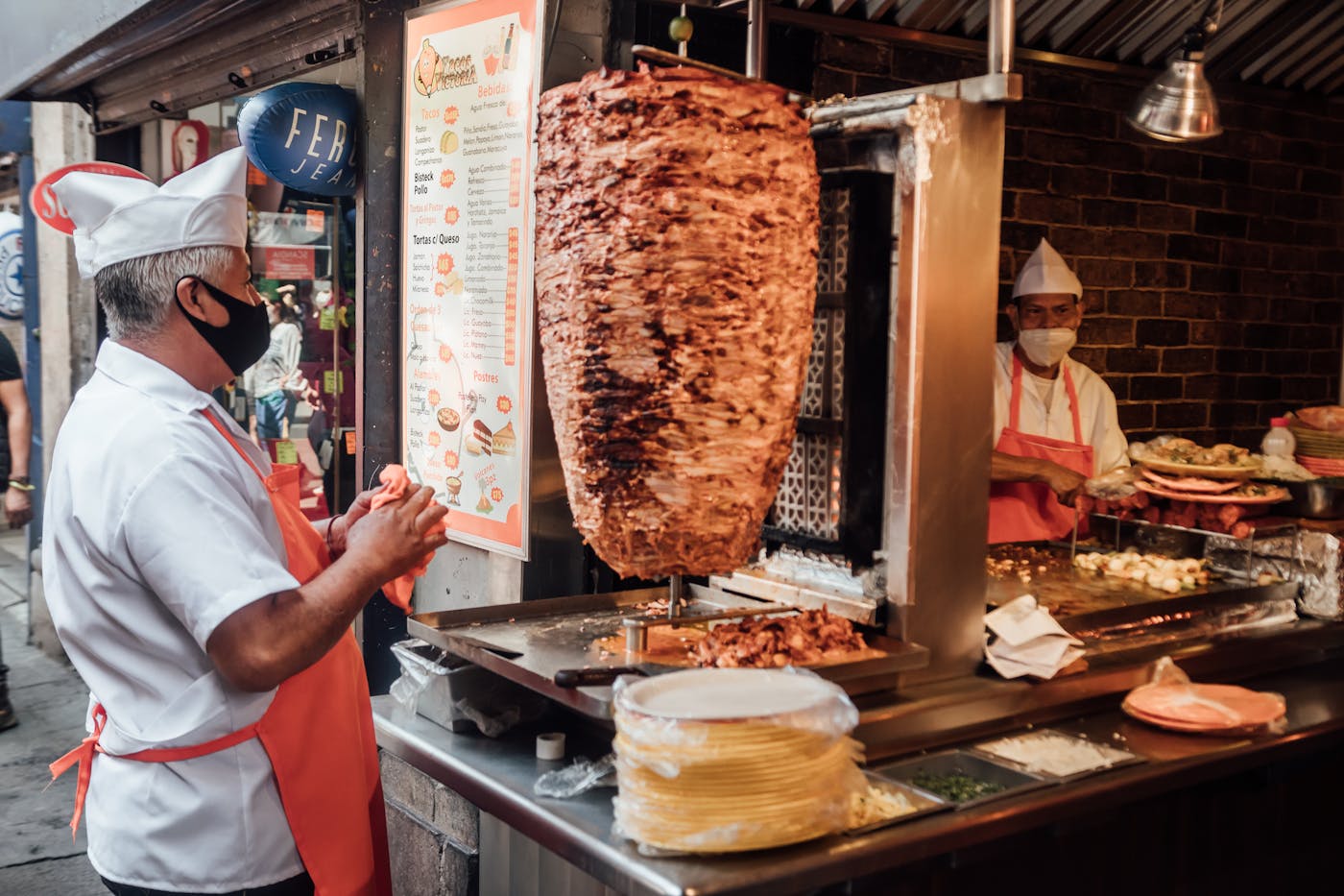 A cook shaving al pastor pork off the vertical trompo