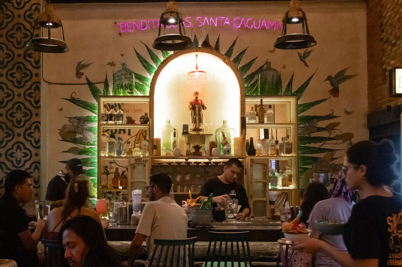 A lively bar with patrons and green arched decor
