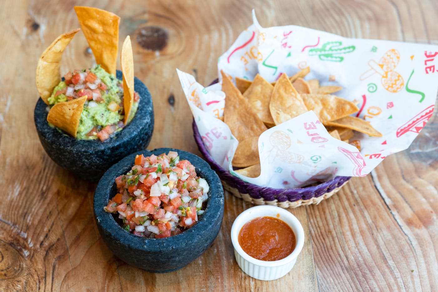 Blue bowls of guacamole and red salsa with tortilla chips