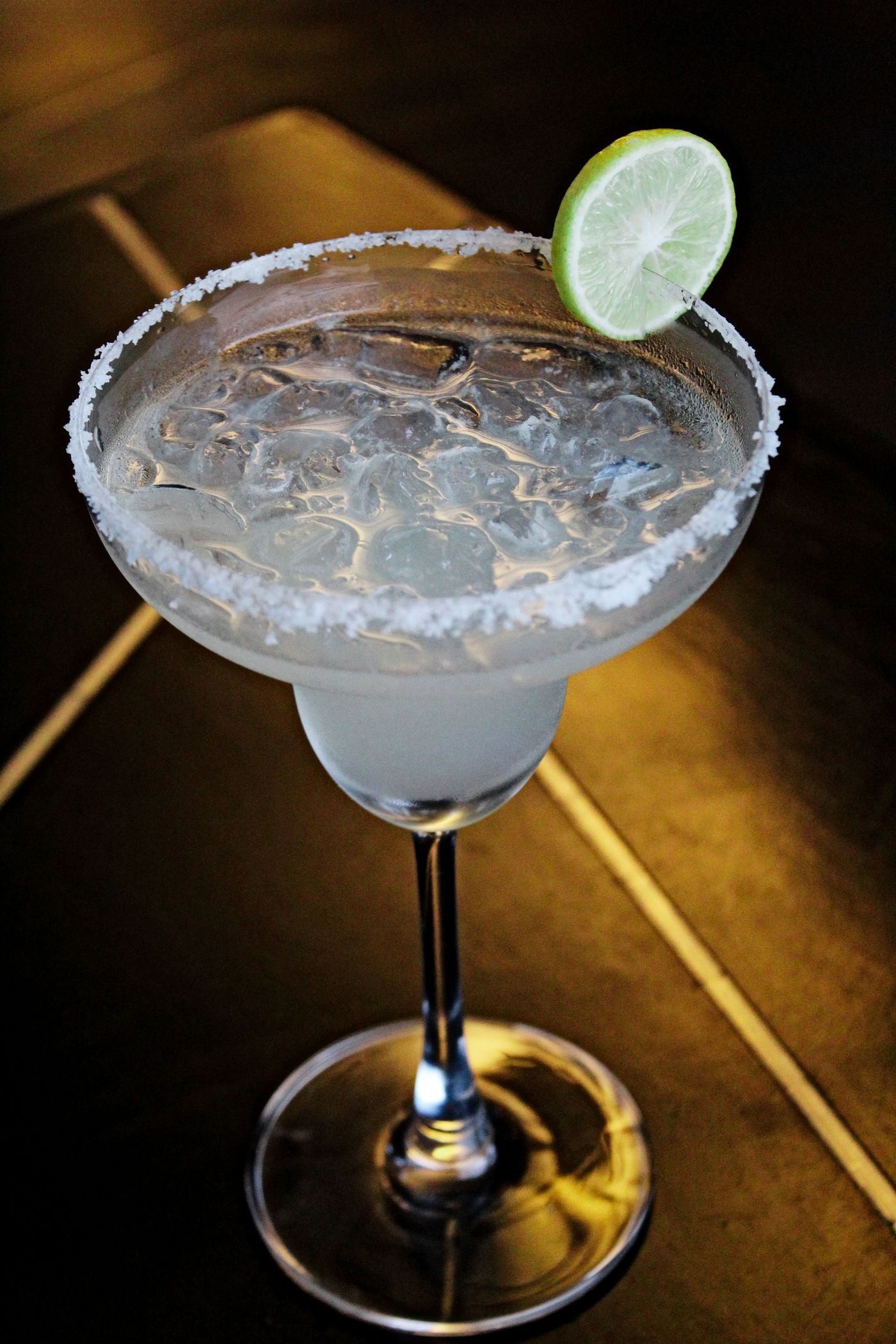 A margarita in a stemmed glass with a salted rim and lime