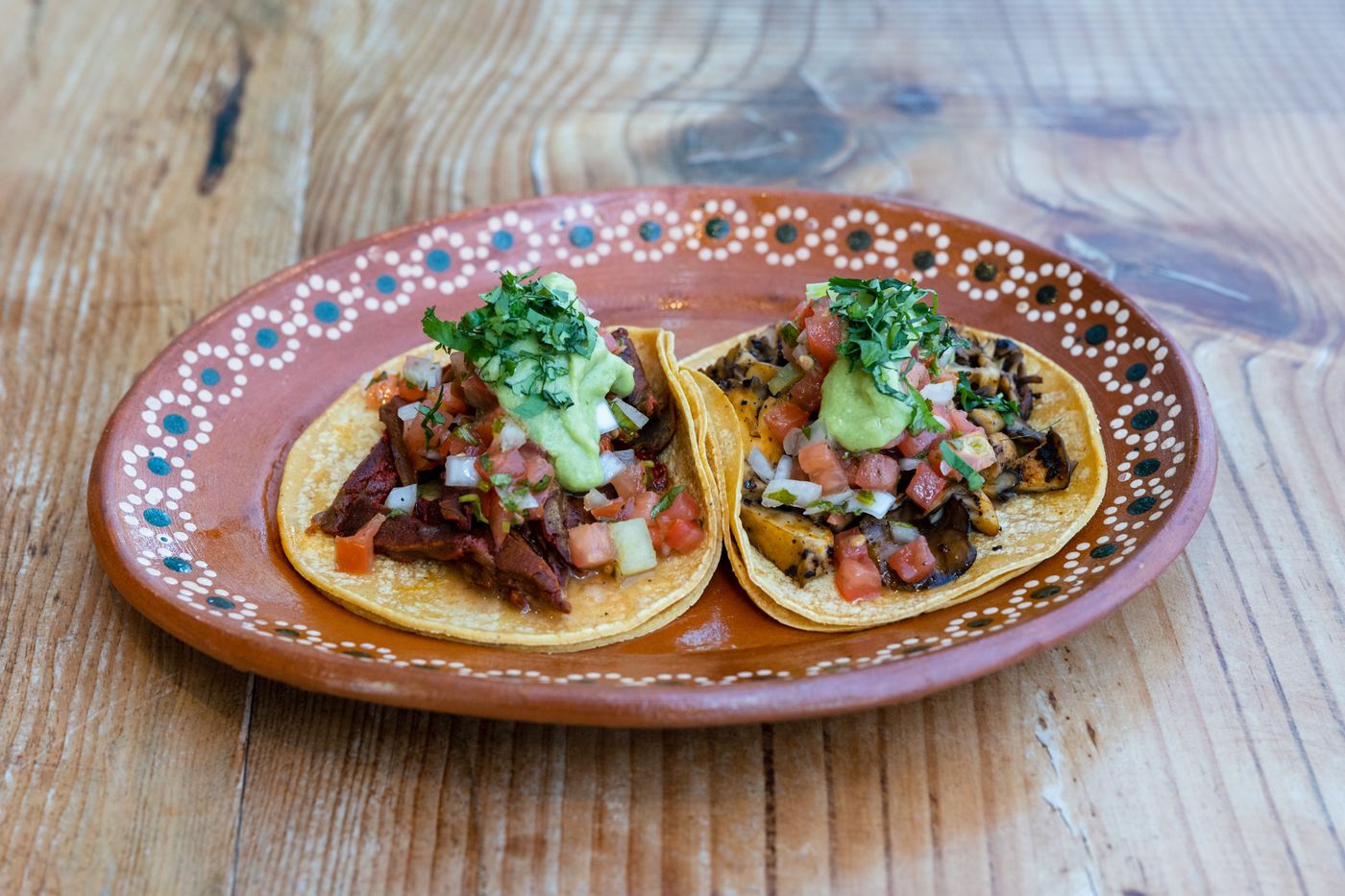 Tacos with meat, onion and cilantro on a painted oval plate