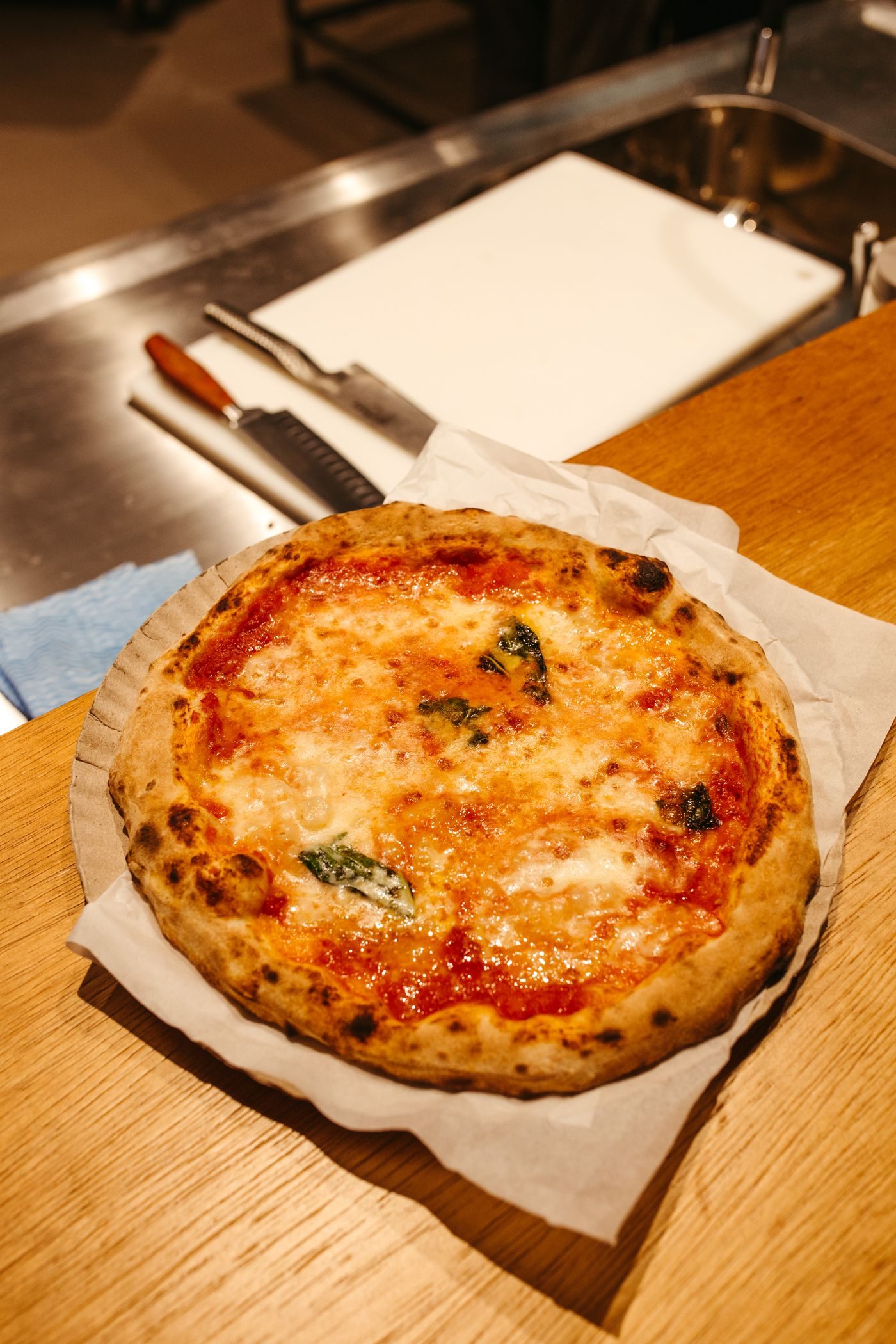 A Margherita pizza fresh from the wood oven, basil and melted mozzarella